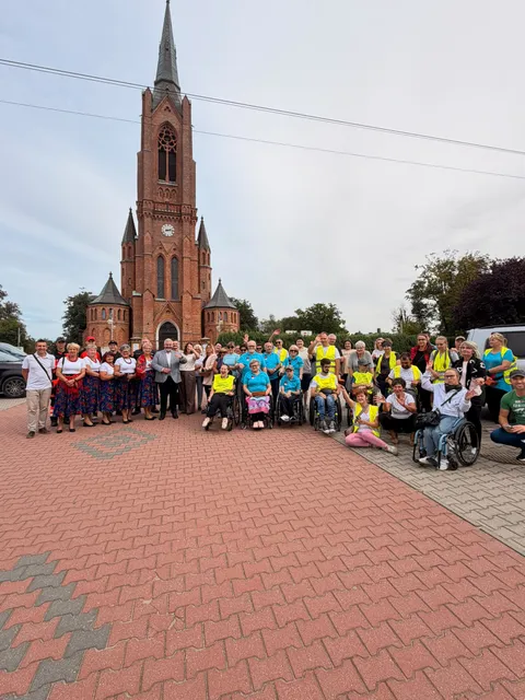 Wspólne zdjęcie uczestników, opiekunów i mieszkańców przed kościołem na trasie sztafety.